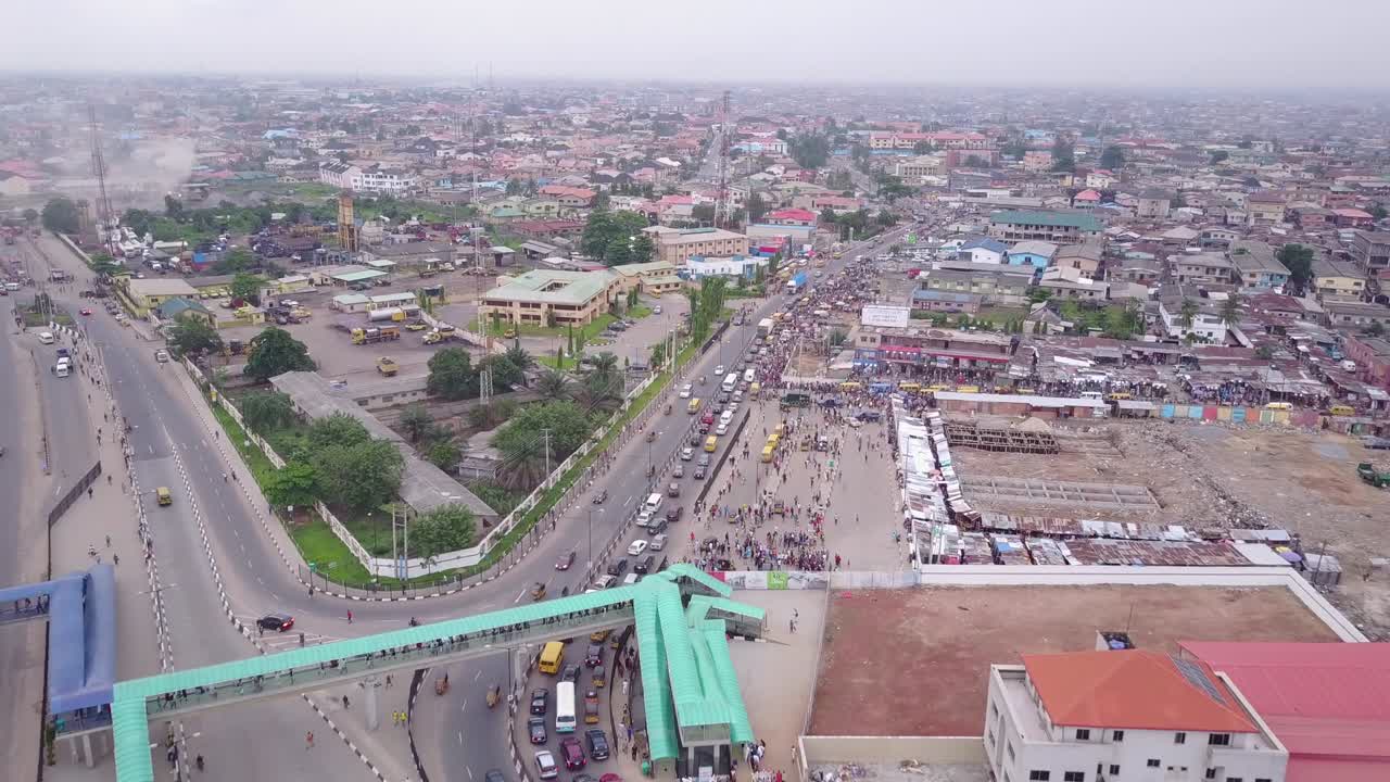 Vista aérea de uma rodovia em Lagos, Nigéria, com uma passarela e carros e caminhões movimentando-se ativamente em meio a um engarrafamento