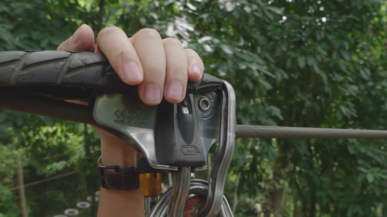 Person holding zipline safety gear in a tropical forest