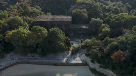 Edificio-Abandonado-En-Okunoshima,-Playa-Reveladora-De-Inclinación-Aérea