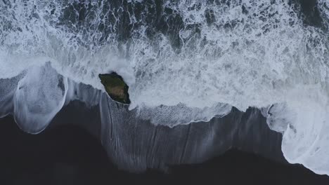 Schaumige-Küstenwellen-Nähern-Sich-Dem-Schwarzen-Sandstrand-Mit-Einem-Einsamen-Felsen-An-Einem-Einsamen-Strand-In-Island