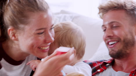 young white couple play with their toddler in sitting room