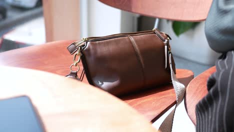 brown leather crossbody bag on wooden table