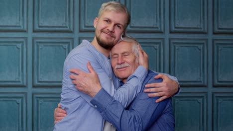 happy excited young man embracing gray-haired old dad or grandfather, male generations family