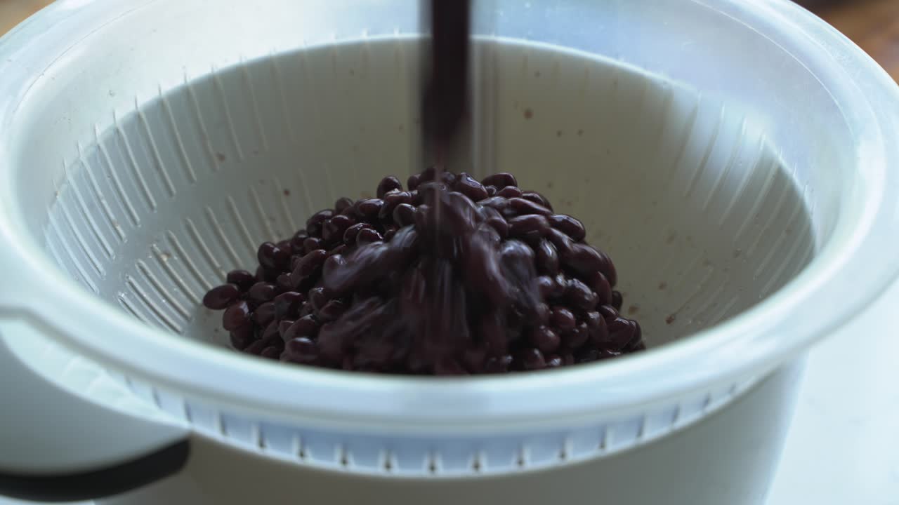 drenando dos latas de frijoles negros para cocinar una comida dos latas de frijoles arroz plátano aguacate cebolla roja y cilantro