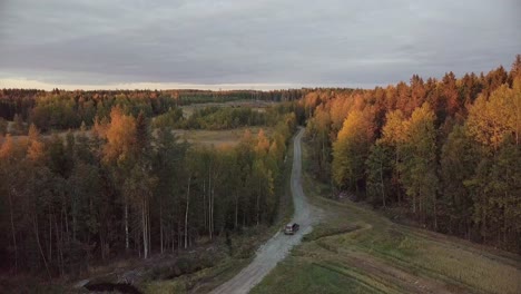 cinematic aerial view of car crossing forest on solitary road