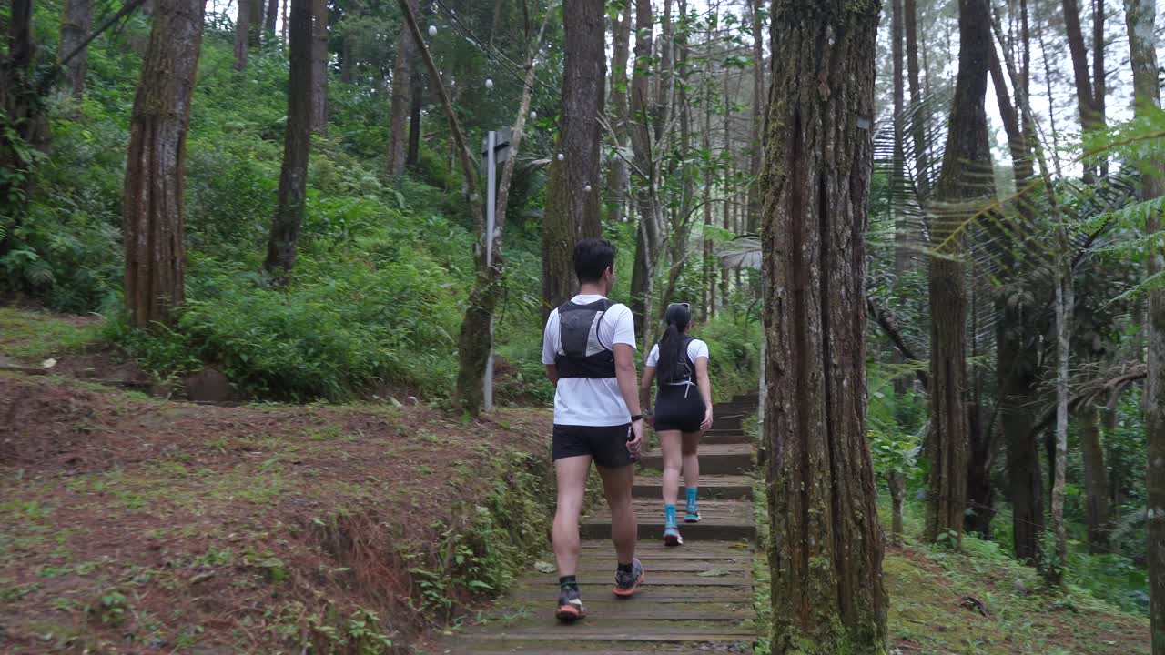 Asian couple walking on forest trail path during outdoor adventure in Indonesia