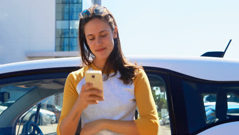 mujer usando teléfono móvil cerca de su coche 4k