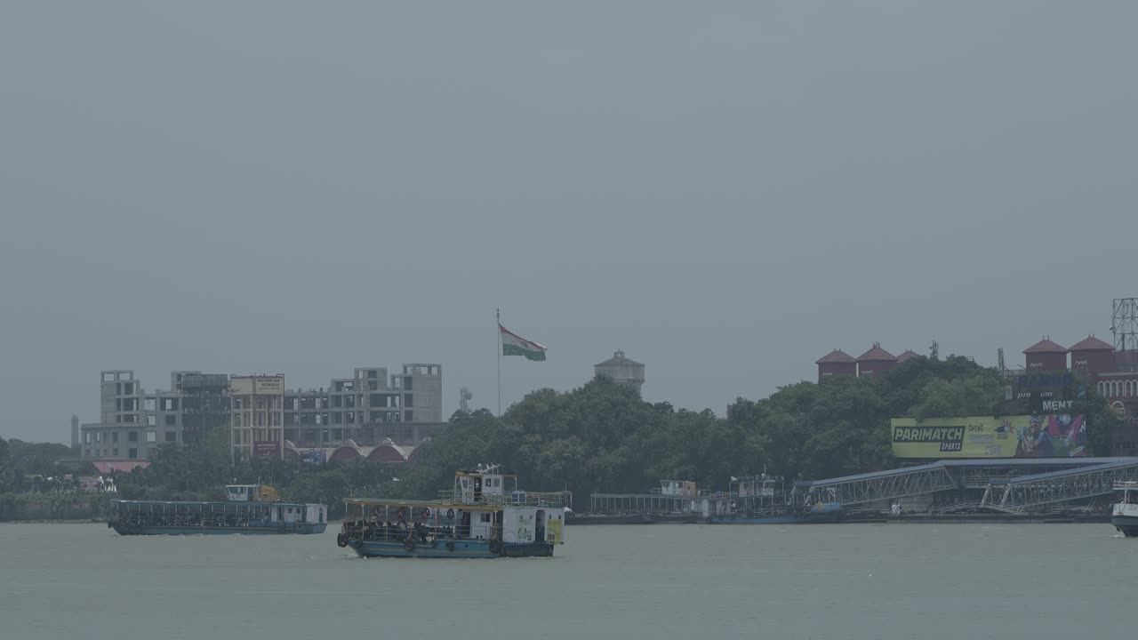 Boats and ferries on a river with an Indian flag and urban skyline