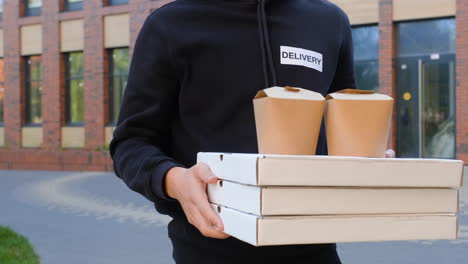 young man holding pizza boxes