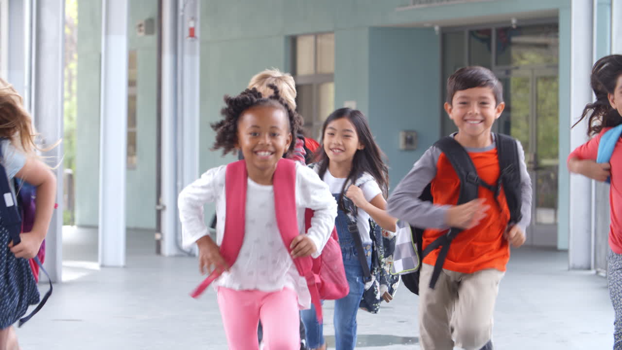 grupo de niños de escuela primaria corriendo en un corredor de la escuela.