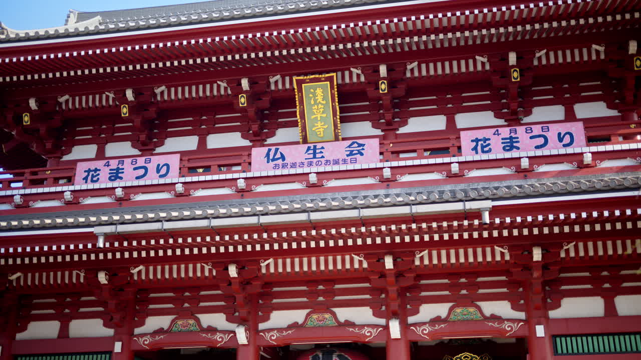 The Senso-ji temple surrounded by cherry blossoms in daylight in Asakusa, Tokyo, Japan. Translation: " Busshokai flower festival"