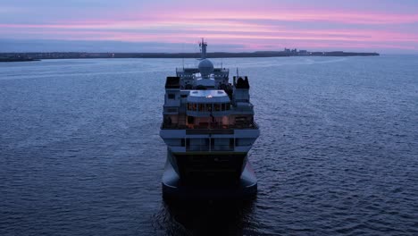 stern view of national geographic explorer boat in calm water with purple sunset