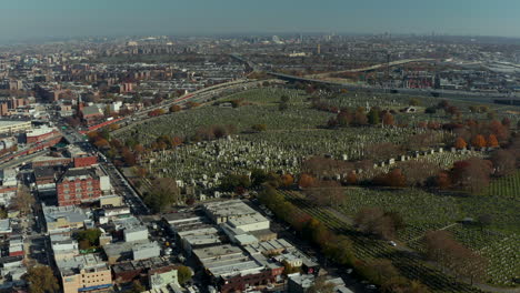 Aerial-panoramic-view-of-large-city.-Highway-interchange-near-large-Calvary-Cemetery.-Tilt-down-on-rows-of-tombstones-in-green-lawn.-Queens,-New-York-City,-USA