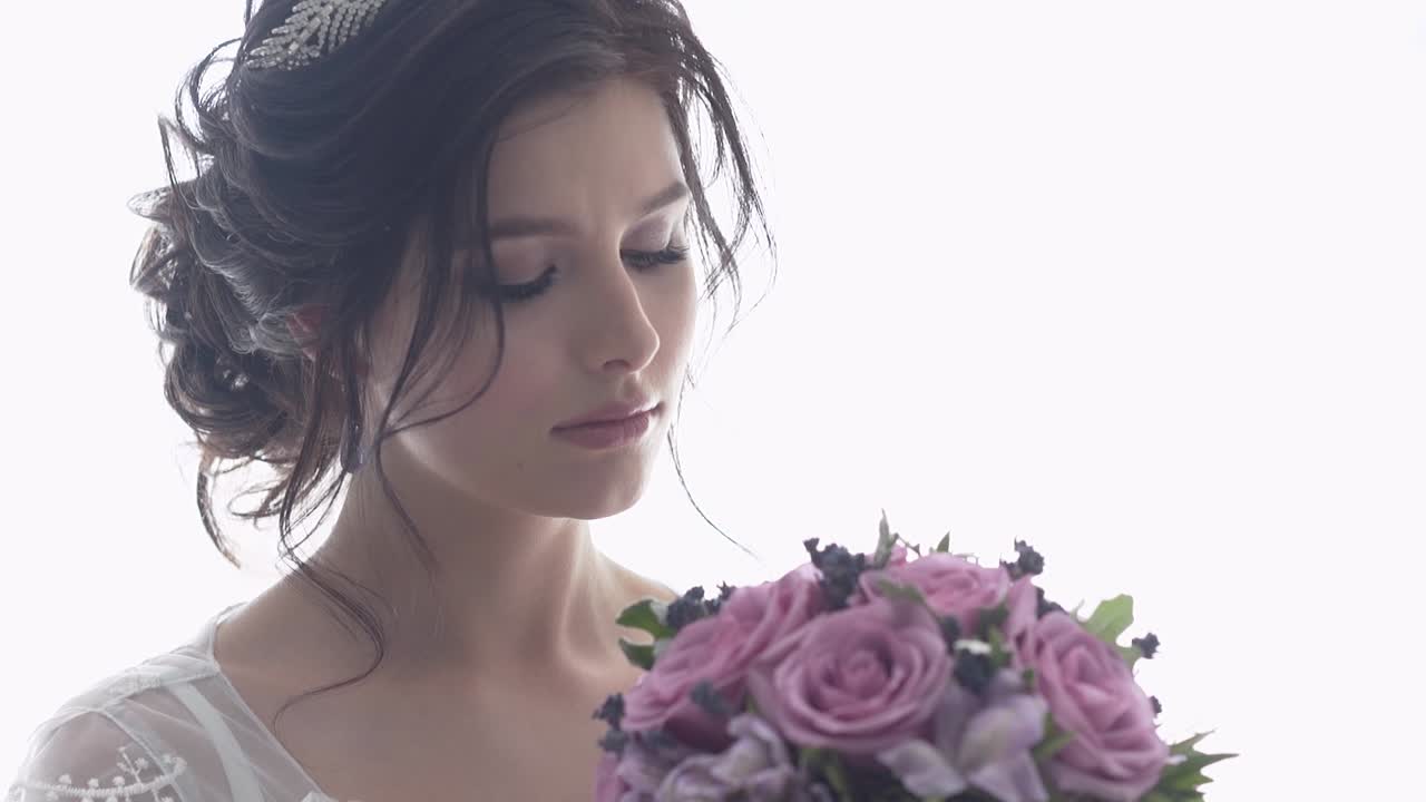slow motion giovane sposa guarda il bouquet di rose viola