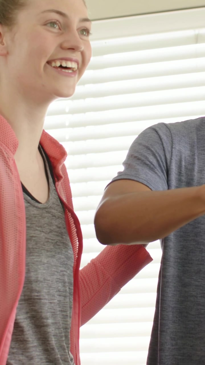 Vertical video: Reacting to man's reach, woman in pink jacket leaning at counter, preparing salad
