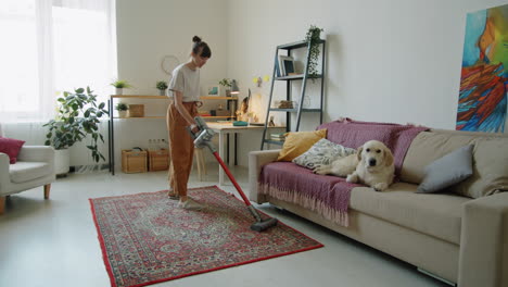 Frau-Staubsaugt-Zu-Hause,-Während-Der-Hund-Auf-Dem-Sofa-Liegt