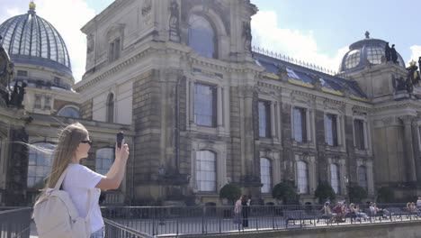 a woman is taking a picture of a building with her phone