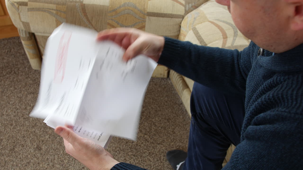 한 남자가 집에서 빚 편지를 열고 있다