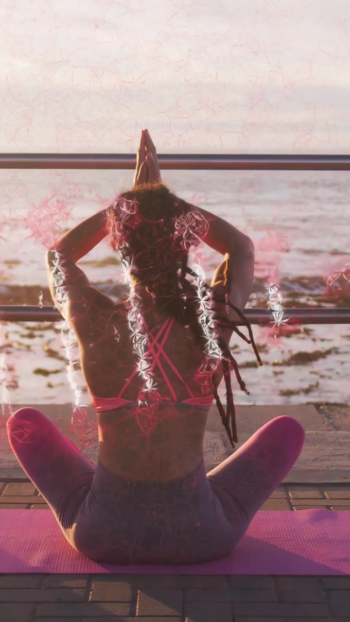 Video verticale: Donna seduta su un tappetino rosa in riva al mare, si sistema i capelli e solleva i palmi per lo yoga, con scintille.