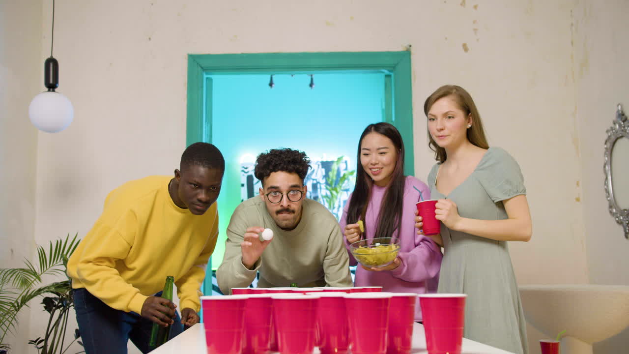 felices jóvenes amigos multiétnicos jugando al pong de cerveza en casa