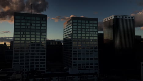 Sunset-time-lapse-of-city-buildings-in-downtown-Ottawa,-with-fast-moving-clouds-and-reflections