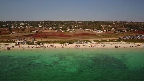 Drone-moves-sideways-to-show-a-sandy-beach-with-people-on-it