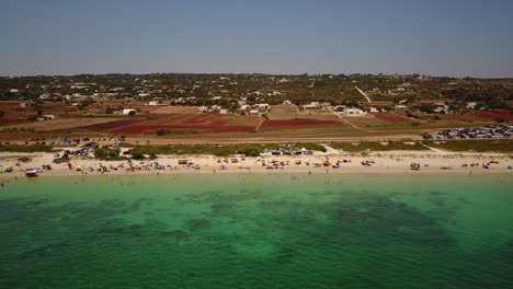 el dron se mueve hacia los lados para mostrar una playa de arena con gente en ella