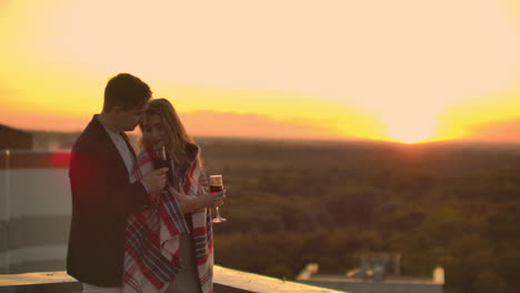 Loving-couple-is-sitting-on-the-roof-of-the-house.-In-the-distance-the-lights-of-the-night-city.