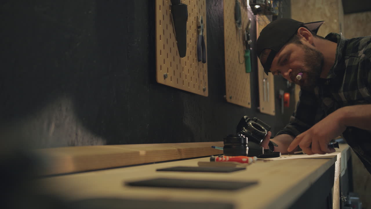 Young man fixing camera on workbench