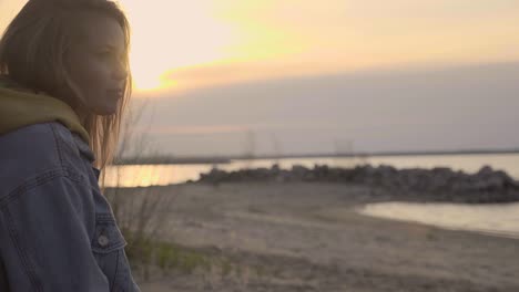 sunset autumn beach and sad girl sitting on tree