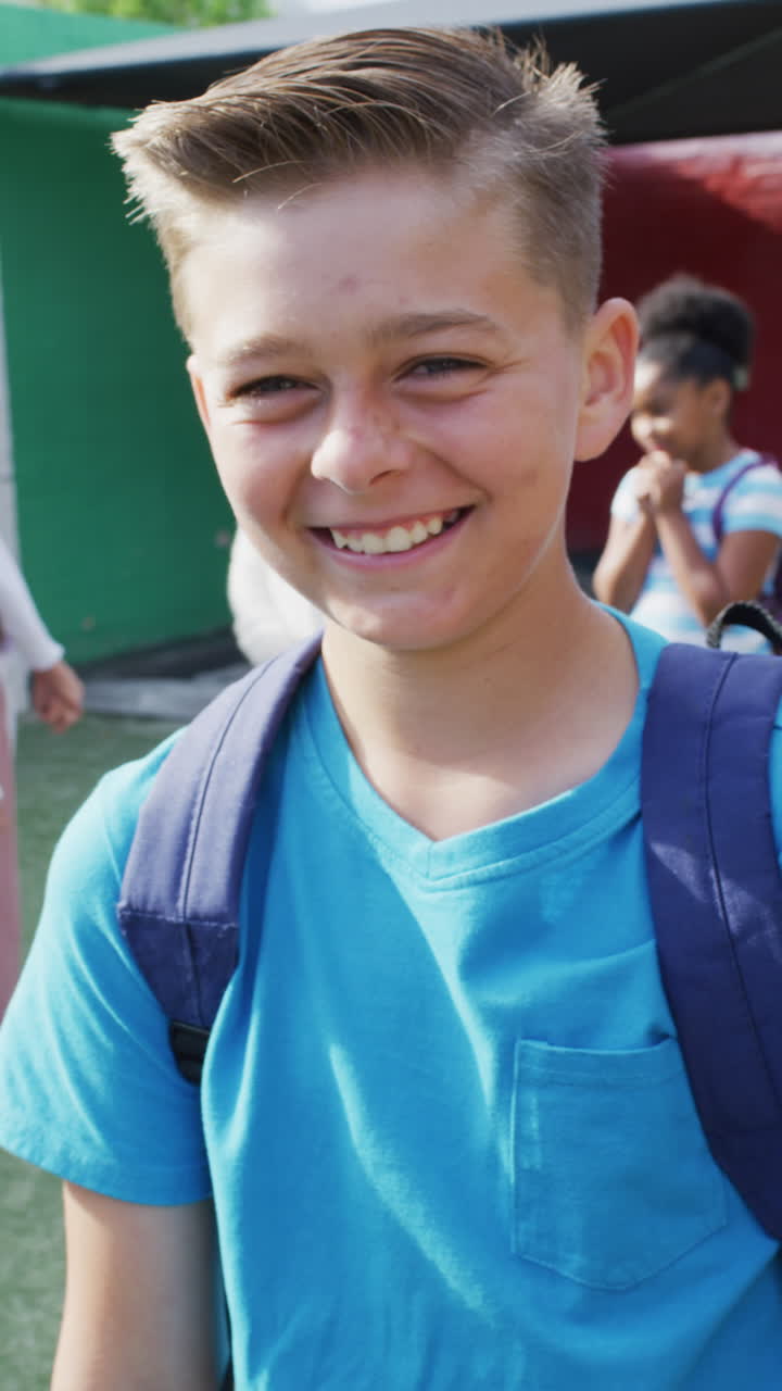 Vertical video of portrait of happy caucasian schoolboy in school