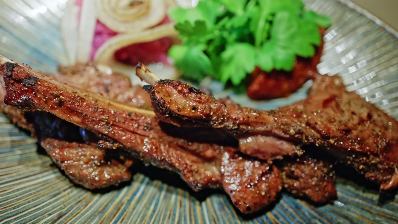 Un piatto di carne alla griglia servito su un piatto decorativo, guarnito con erbe fresche e verdure.