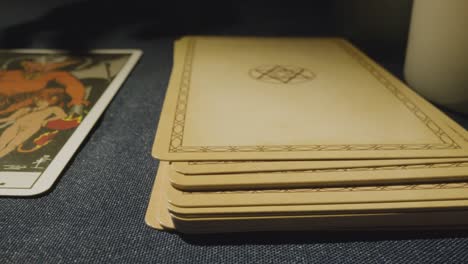 close up shot of person giving tarot card reading laying down the devil card on table