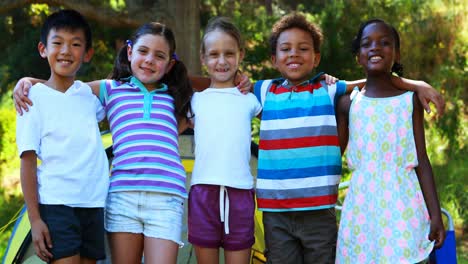 Kids-standing-with-arms-around-outside-tent-at-campsite