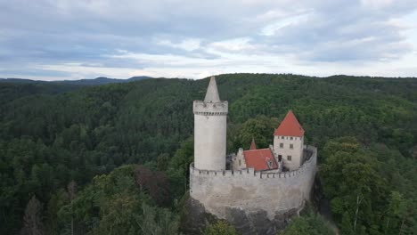 flight of a drone camera around the tower of a medieval castle in the middle of endless forests