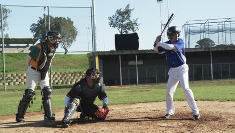 male baseball players and male umpire playing baseball, catching the ball on a pitch, slow motion