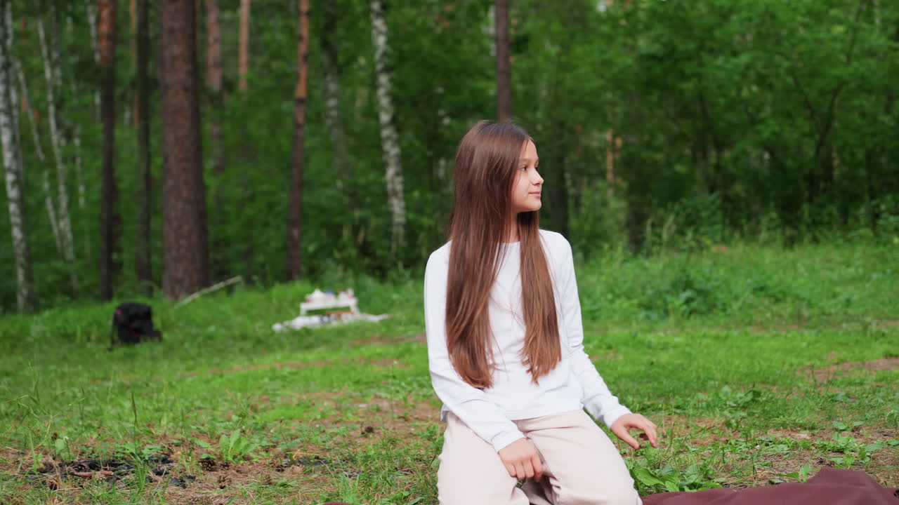 싱그러운 녹음으로 둘러싸인 한적한 숲 속 공터에서 십 대 소녀가 무릎을 꿇고 앉아 긴 머리를 정리하며, 자연광과 고요한 야외 분위기 속에서 평화로운 자기 관리의 순간을 보여주고 있어요.