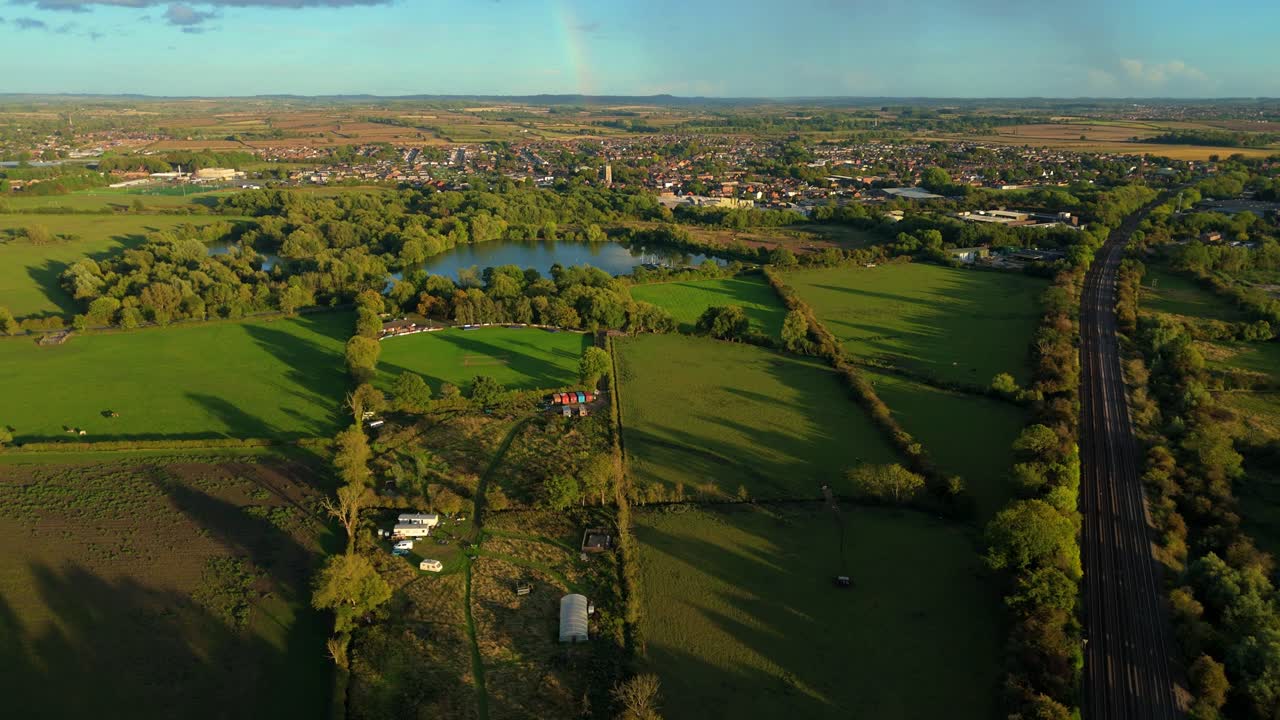 Aerial view of rural landscape bathed in golden light at sunset, lush green fields rolling hills, United Kingdom