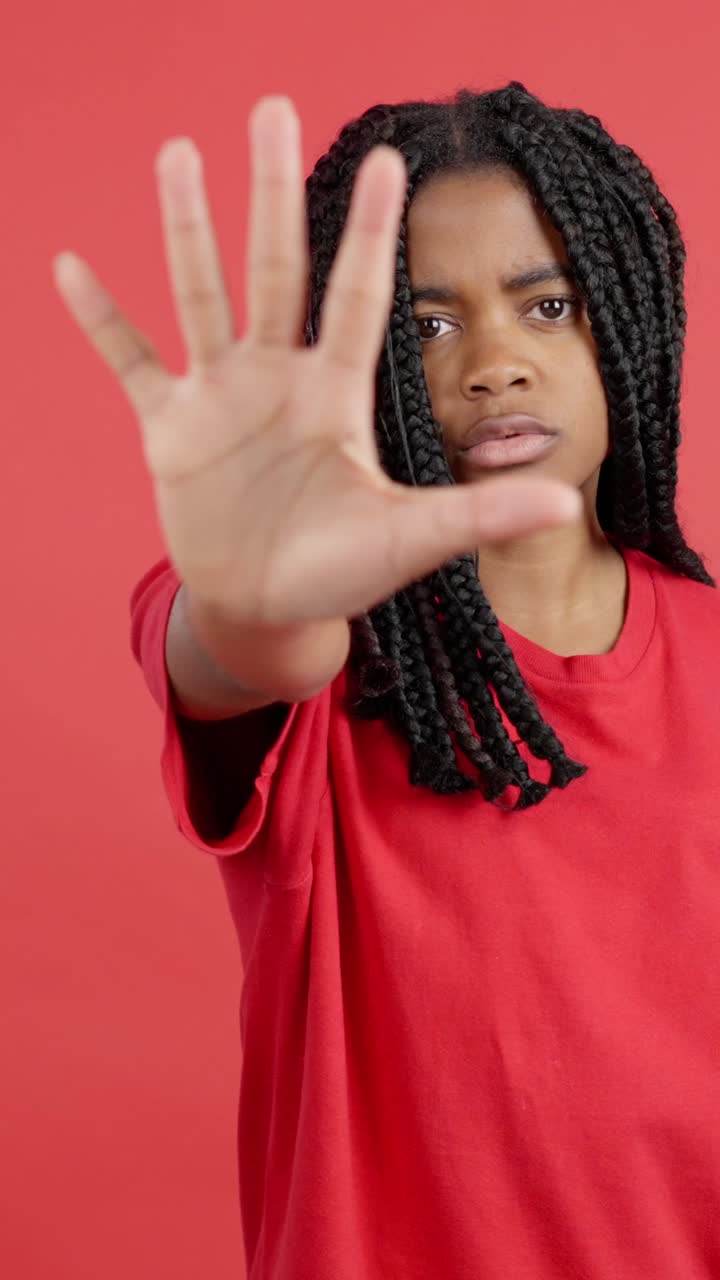 Young woman with braids holding hand up
