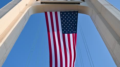 Panorámica-Hacia-Abajo-De-La-Torre-Del-Puente-Mackinac-Y-La-Bandera-Americana-Ondeando