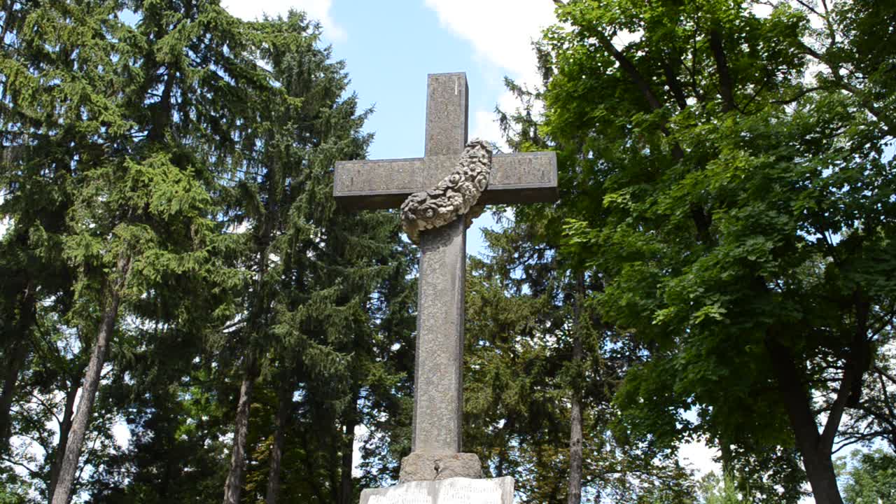 Kříž na pozadí stromů. Lvov, Ukrajina. Lychakovský hřbitov, historický a pamětní areál (od roku 1991) ve Lvově v historické čtvrti Lychakov, jeden z nejstarších hřbitovů Ukrajiny.