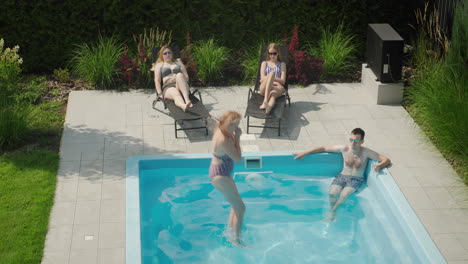 a cheerful family is relaxing by the pool, a woman jumps into the water. enjoying a warm summer day