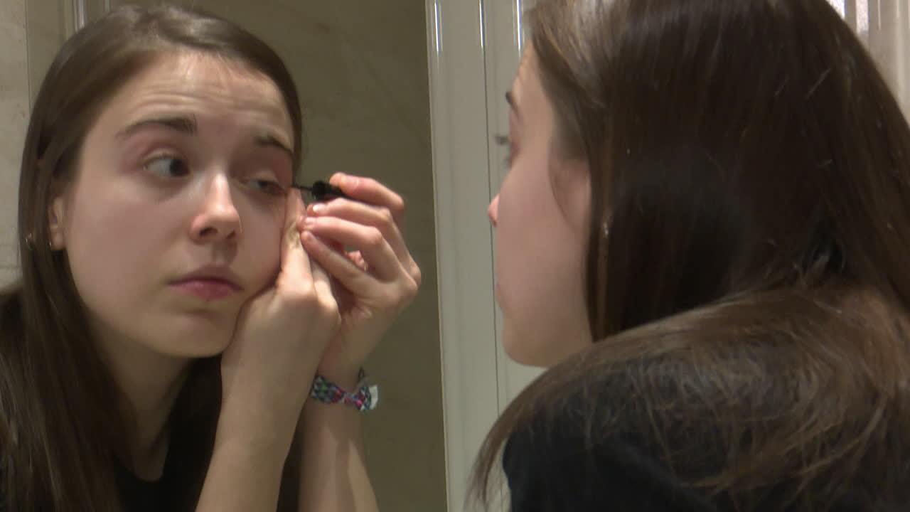 Young Woman Applying Eyeliner in Bathroom