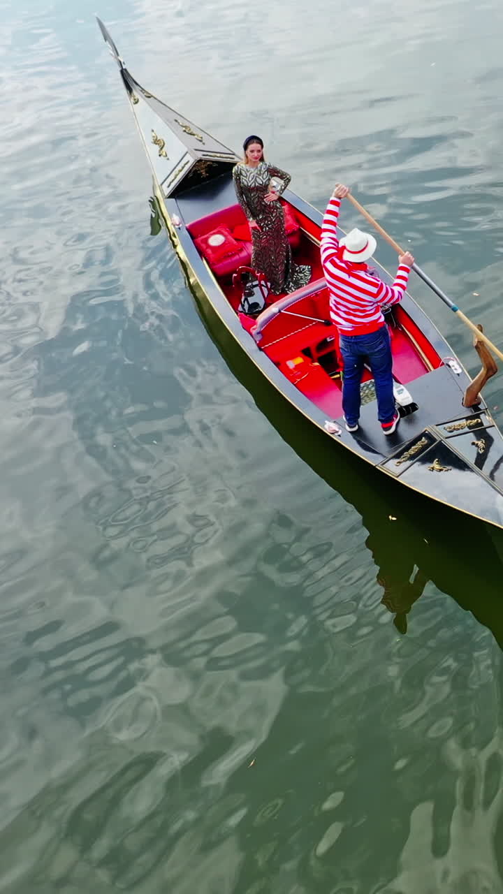 Beautiful woman riding in gondola. Luxury woman travels in a boat along the river in Venice, Italy. Aerial view. Vertical video