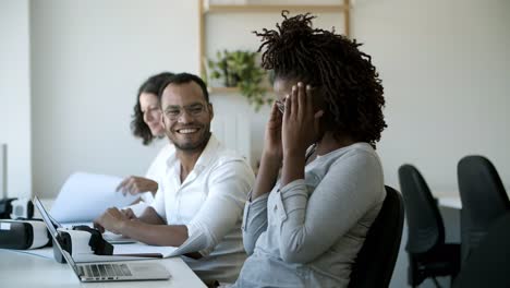 compañeros alegres hablando y riendo durante el trabajo