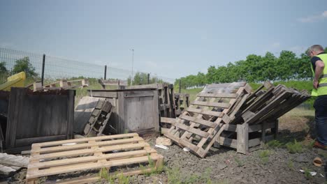 person wearing high-visibility jacket moves and checks wooden pallets