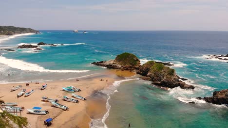 aerial: bird's-eye view huatulco with tourists walking along the picturesque shoreline in mexico