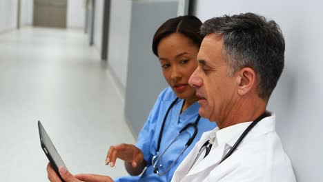 Doctors-discussing-over-digital-tablet-in-corridor