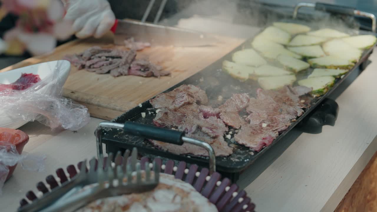 close up of chef grilling thin beef slices and vegetables on a sizzling griddle