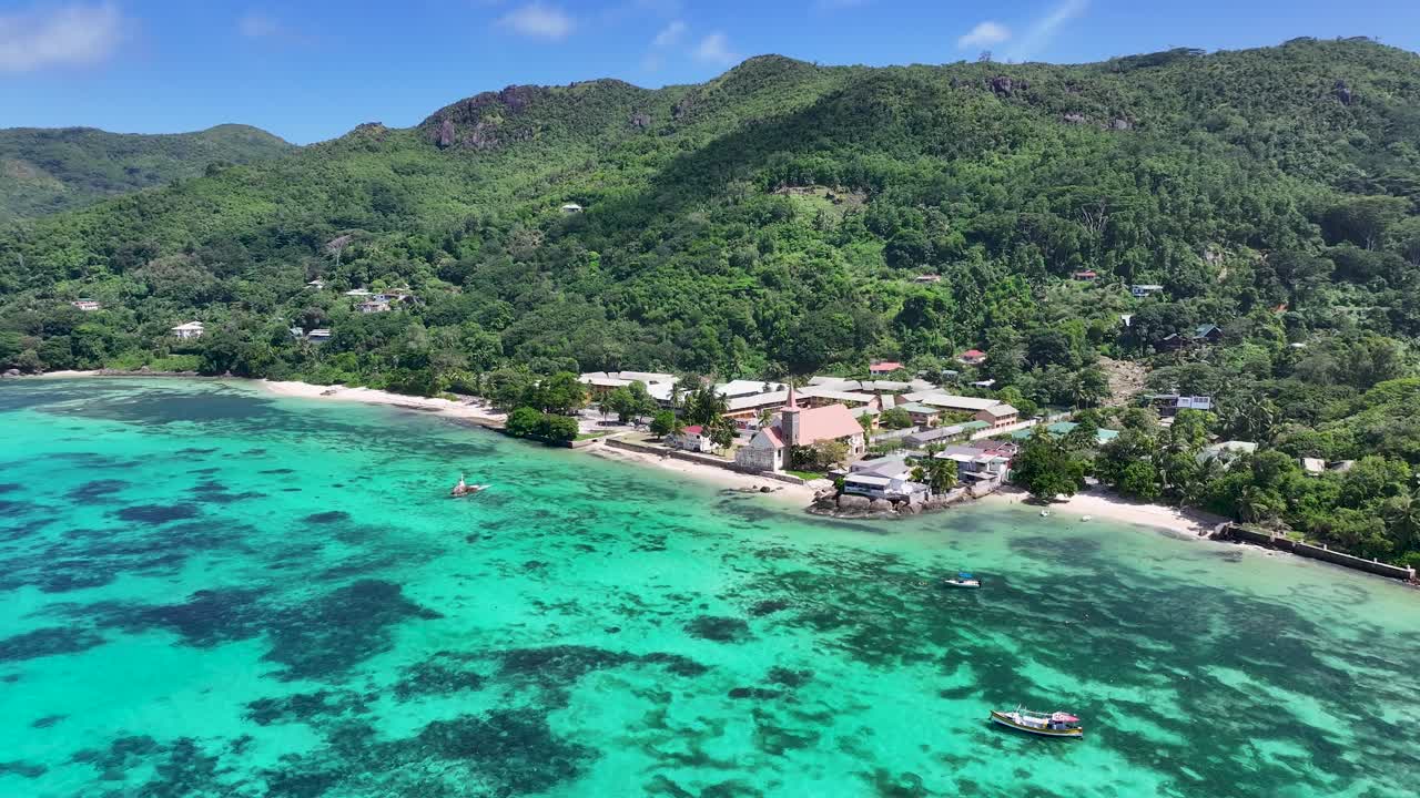 Aerial View of a Tropical Village and Beach with Turquoise Waters and Lush Mountains